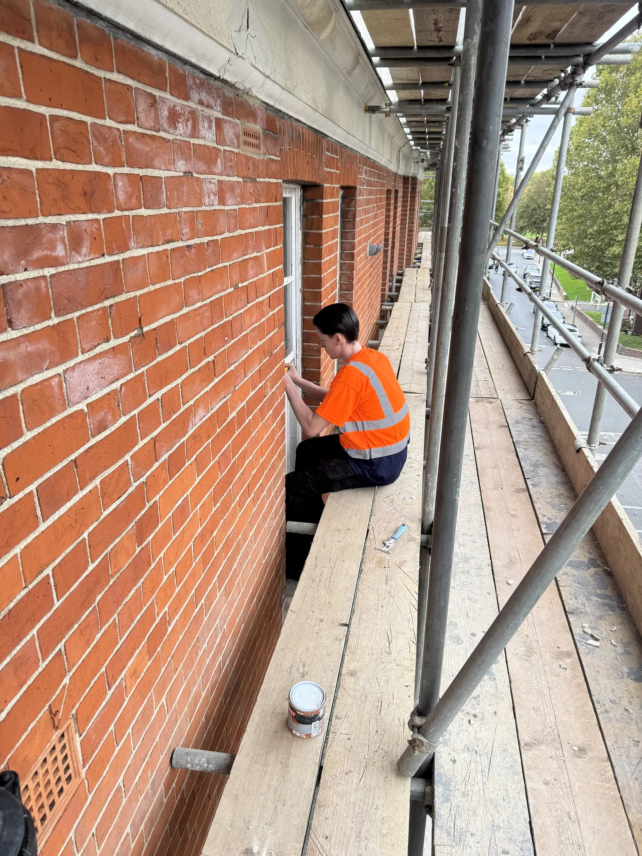 Community Heroes volunteer painting window frames on a scaffold